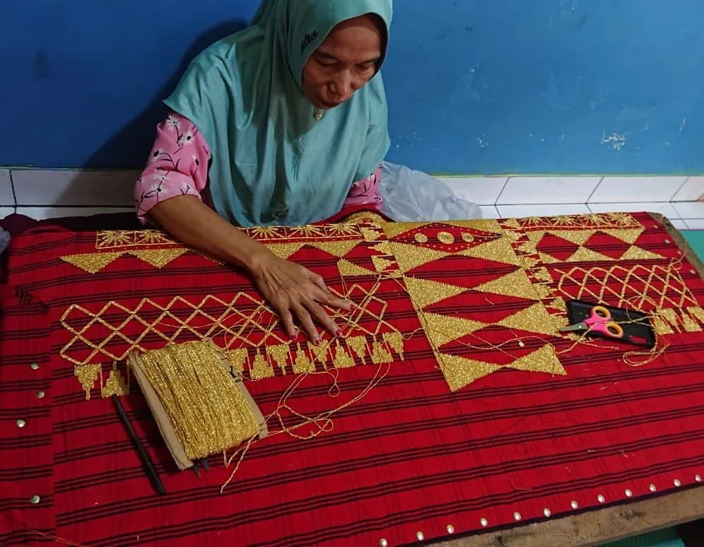 Pengrajin Alyn Tapis sedang menyulam kain tapis menggunakan alat peraga tradisional
