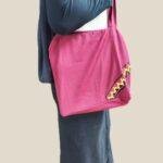 model mengenakan totebag tapis warna merah mmarun dengan aksen motif tapis khas Lampung
